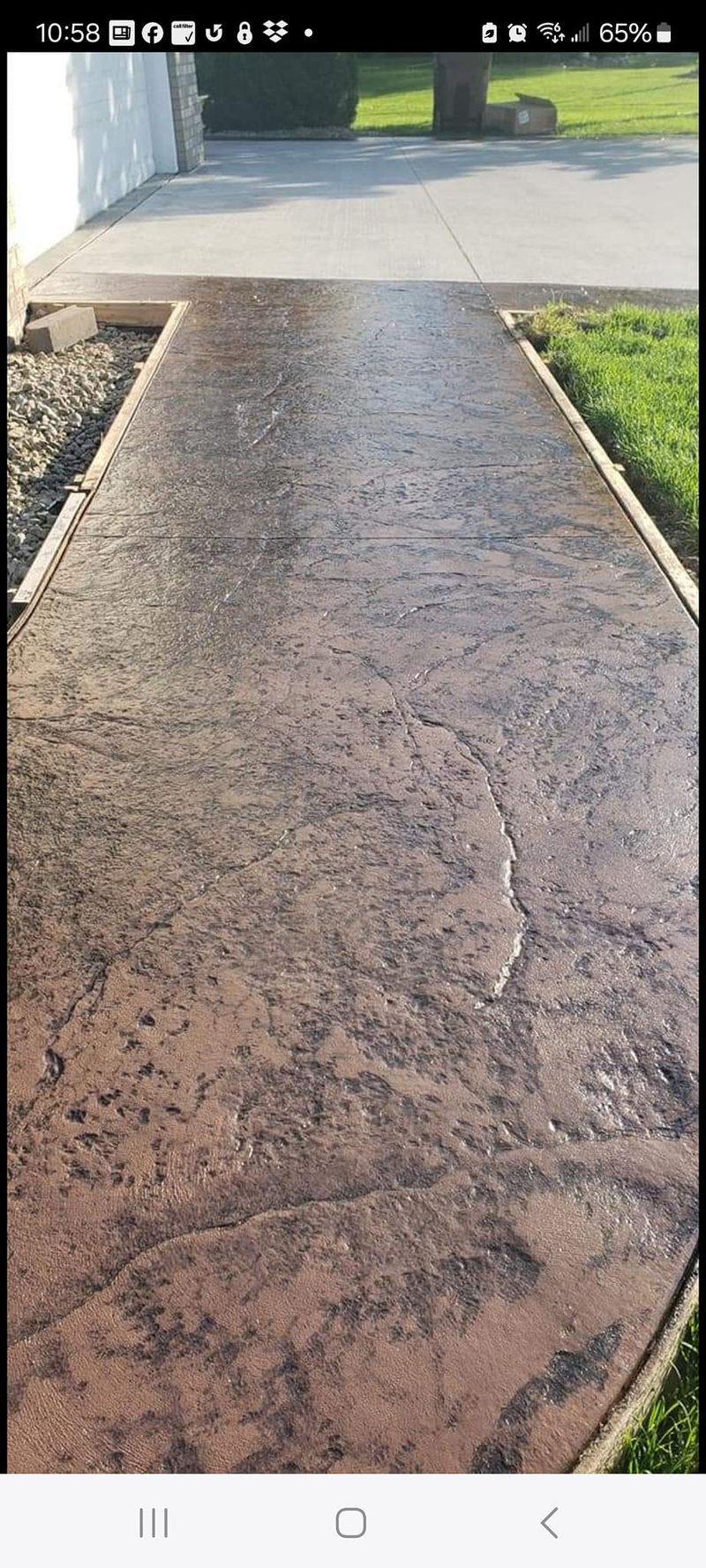 Textured brown stamped-concrete walkway between garage and gravel bed
