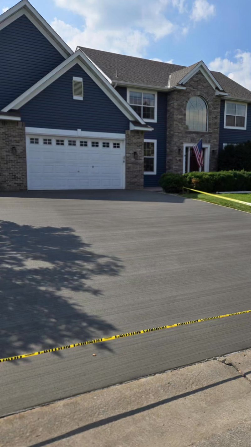 Broom-finished gray driveway in front of a two-story blue house