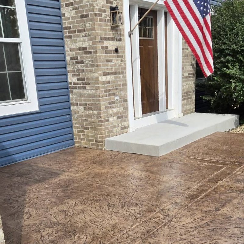 Stamped brown patio and steps leading to a brick home's front door