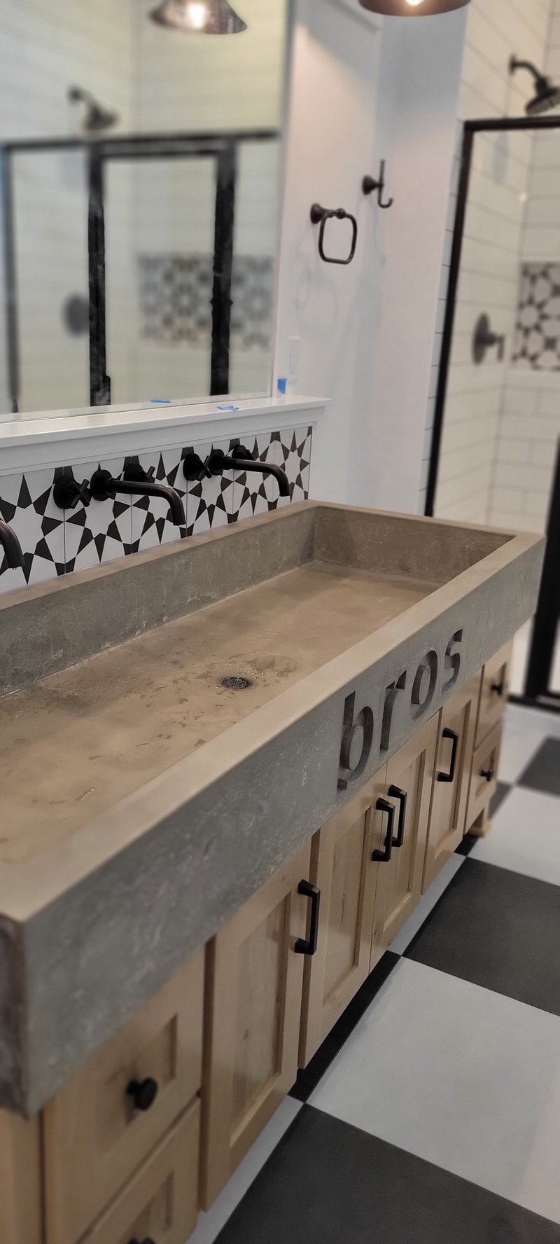 Trough-style concrete bathroom sink with custom lettering carved into the front