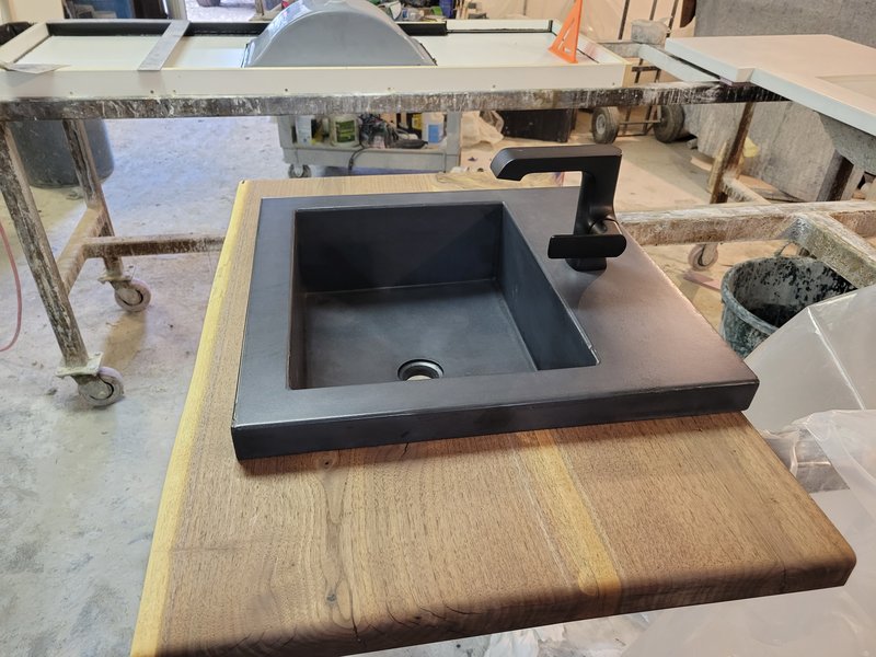 Small black concrete bar sink with an integrated waterfall faucet