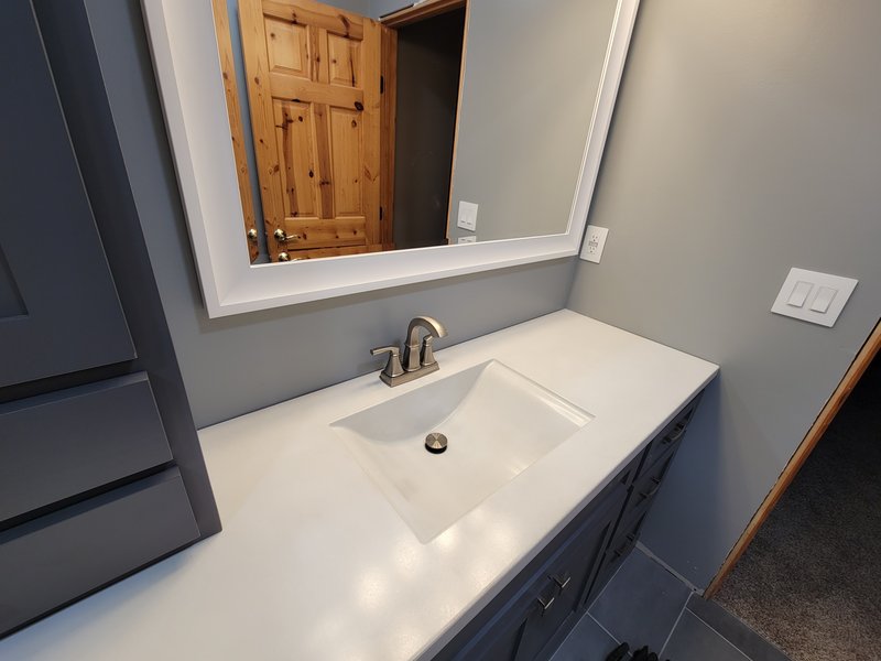 White concrete bathroom vanity sink beneath a mirror