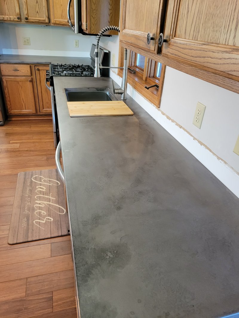 Dark gray concrete kitchen countertop with an integrated sink and gas range