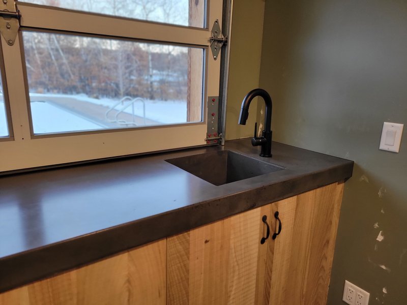 Dark concrete pass-through bar countertop with a black gooseneck faucet