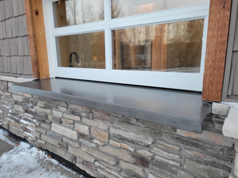 Exterior concrete window sill set into a stone veneer wall