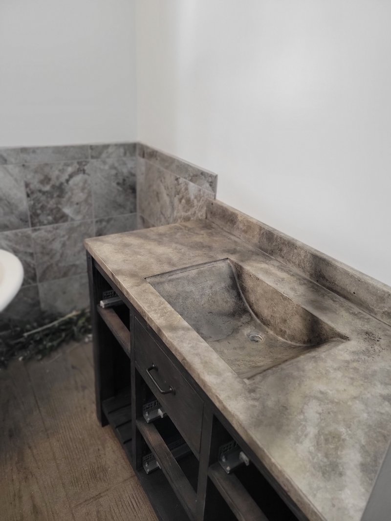 Concrete bathroom vanity top with integrated sink beside a tiled shower wall