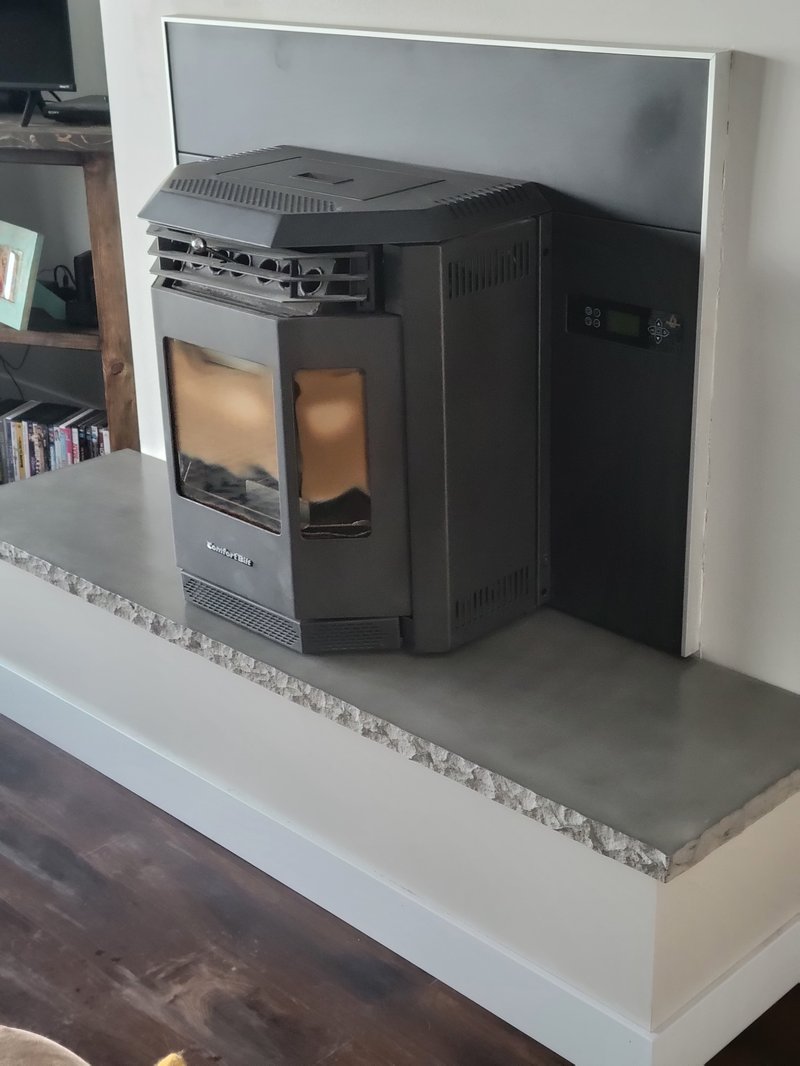 Concrete hearth slab with a rock-faced edge under a pellet stove