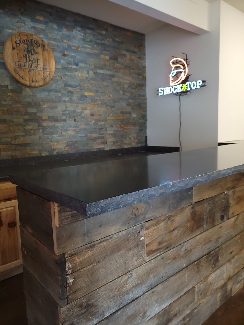 Black concrete bar top with a hammered edge over a reclaimed wood bar