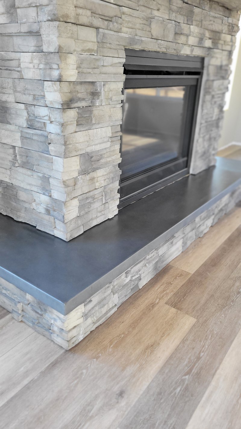 Rock-faced concrete hearth ledge beside a stacked-stone fireplace surround