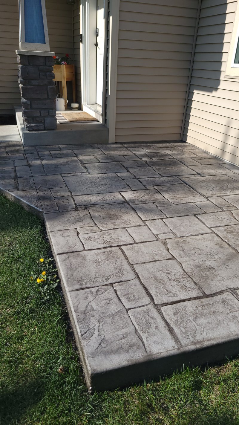 Stamped stone-pattern concrete patio walkway approaching a glass entry door
