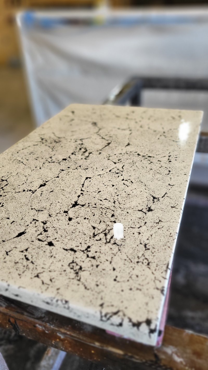 Polished black-and-cream marbled concrete slab staged before installation