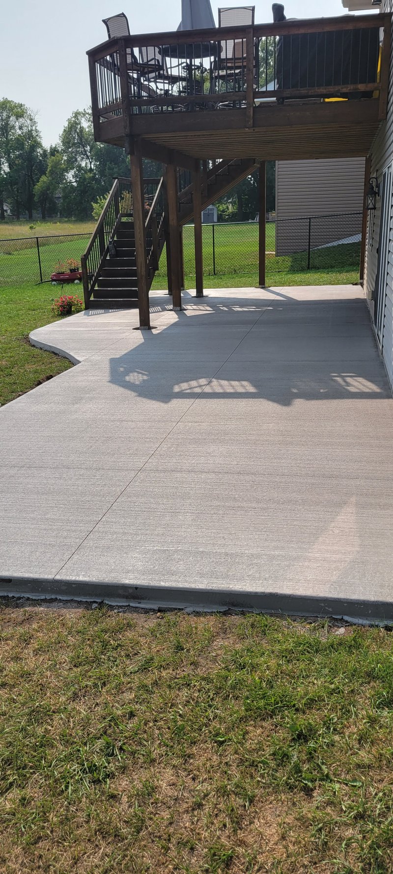 Broom-finished patio slab under a tall two-story deck