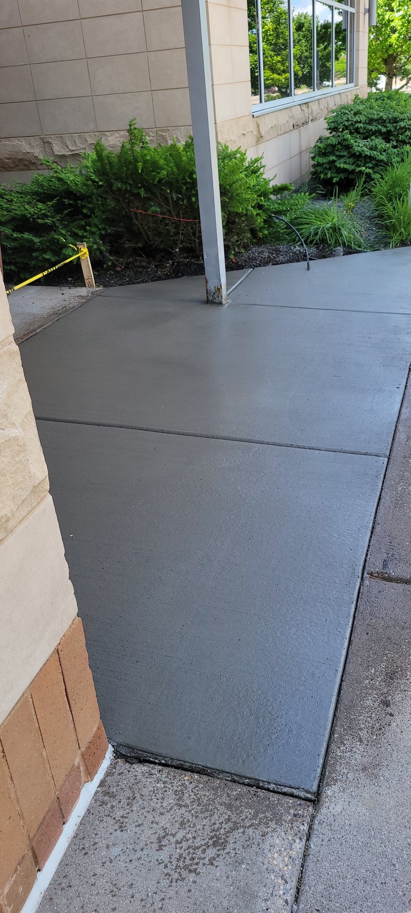 Broom-finished sidewalk beside a stone commercial building entrance