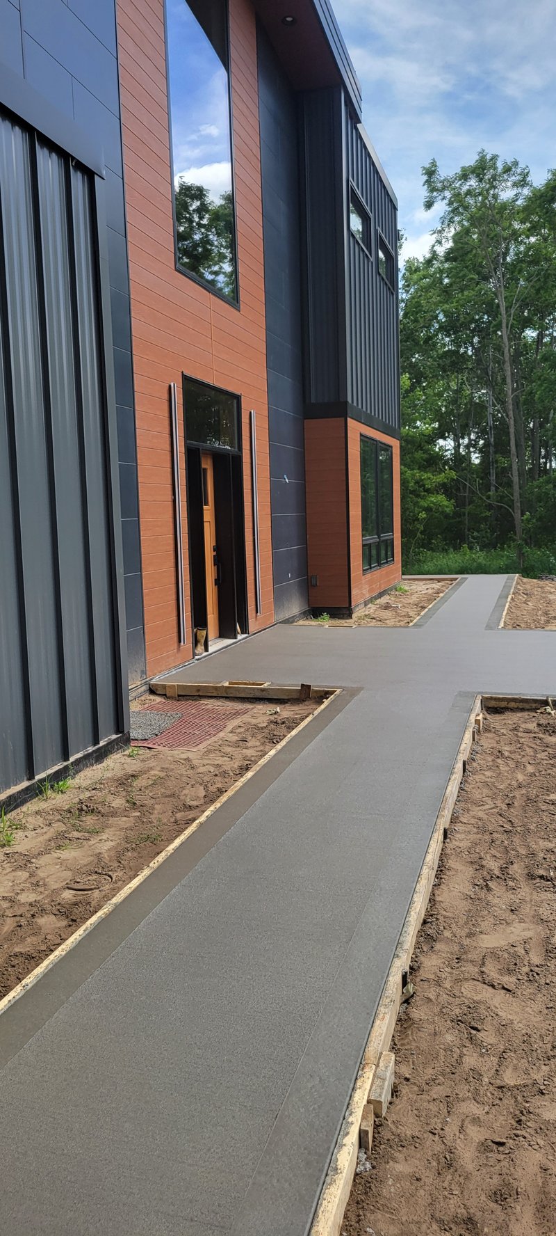 Concrete walkway with wood forms leading to a modern building entrance