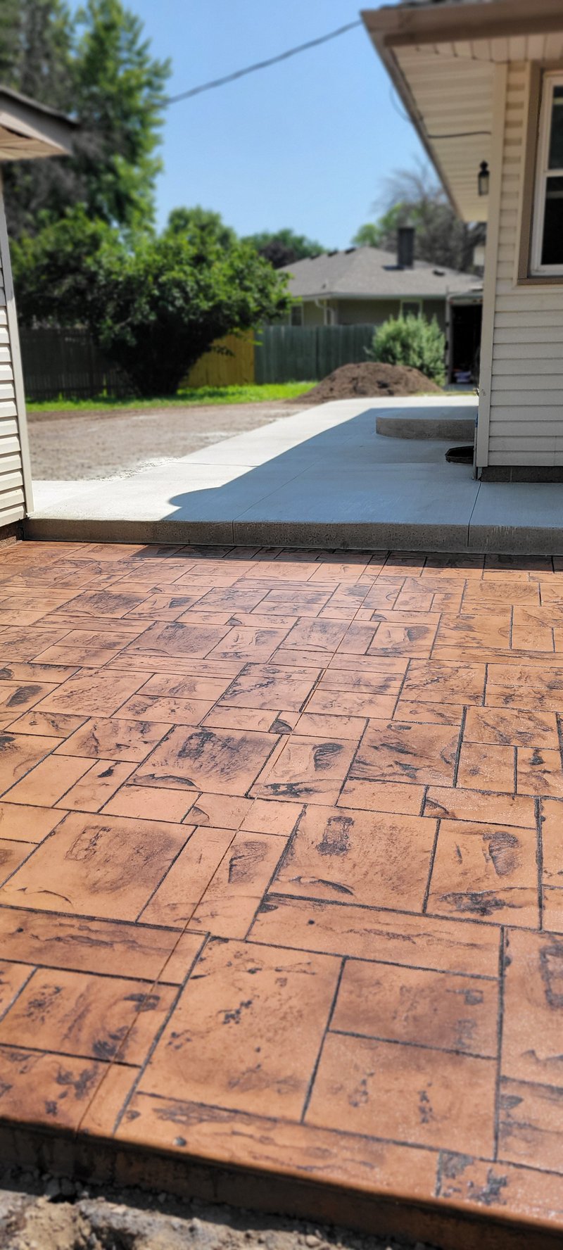 Terracotta-stained stamped concrete patio in a wood-plank pattern