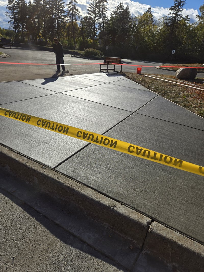 Broom-finished concrete pad walkway near a park bench