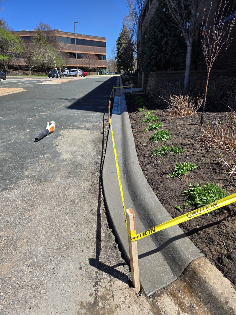 Freshly poured curved concrete curb and gutter along a parking lot planting bed