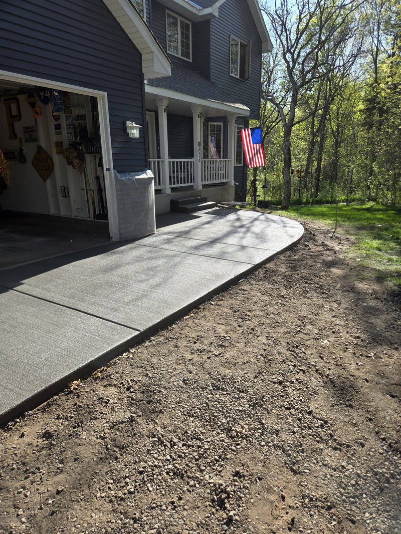 Curved concrete walkway from a garage to front porch steps