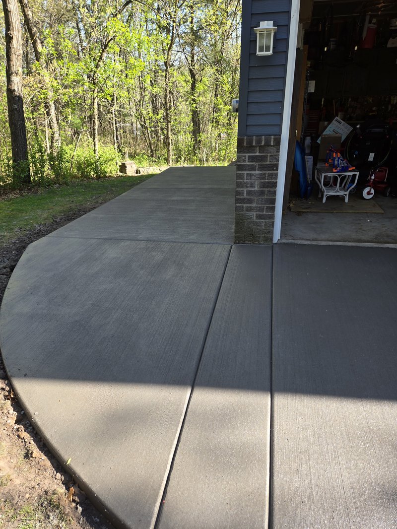 Wide curved walkway connecting a garage to the driveway past a brick column