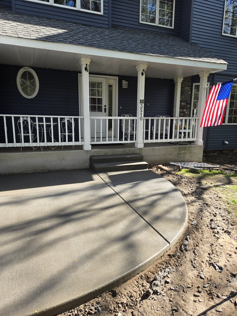 Curved concrete walkway with steps up to a blue house's covered porch
