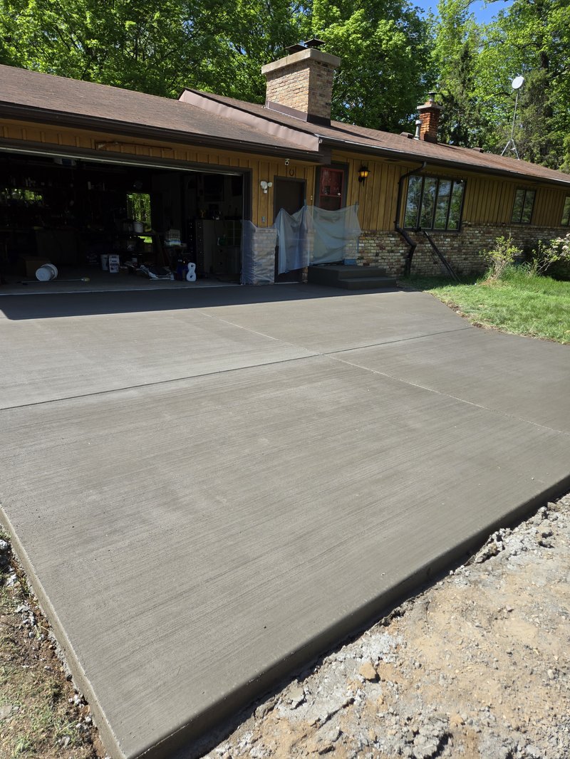 Broom-finished driveway leading to the garage of a brown ranch house
