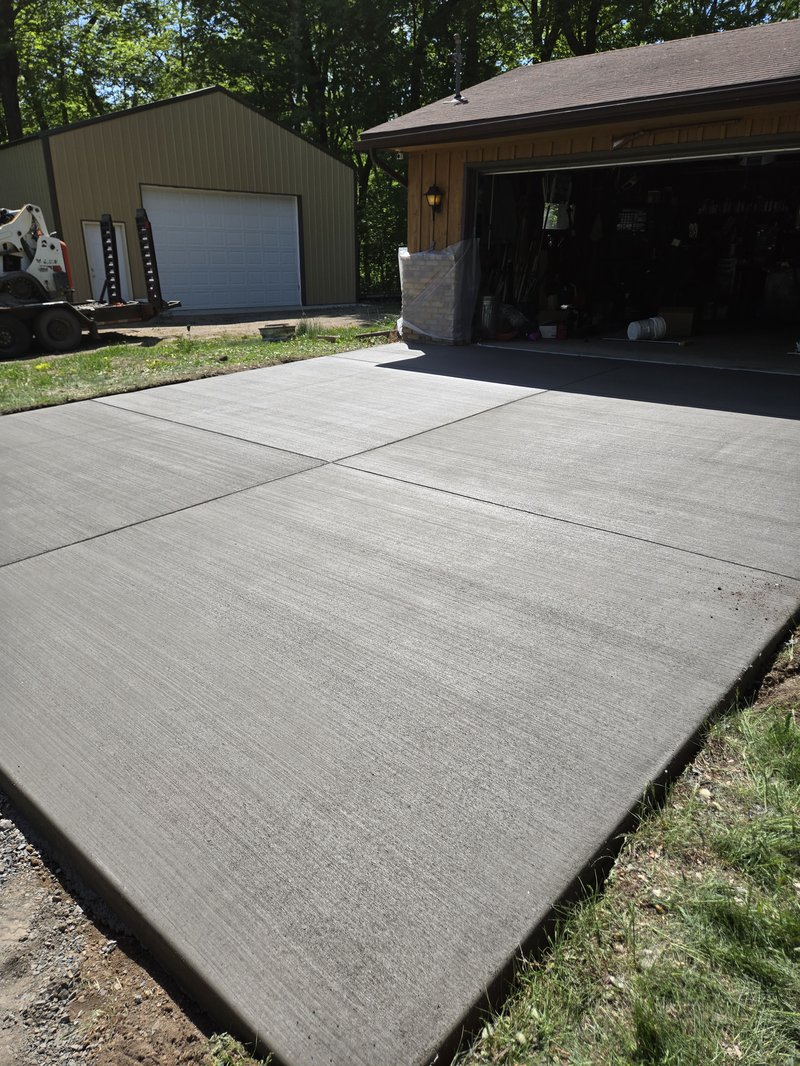 Broom-finished driveway between a garage and a separate metal pole barn