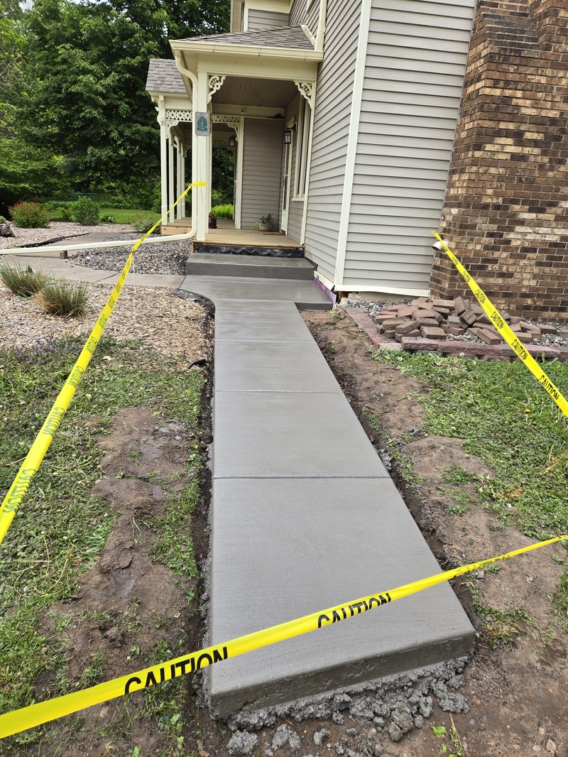 Freshly poured curved walkway to a Victorian-style porch