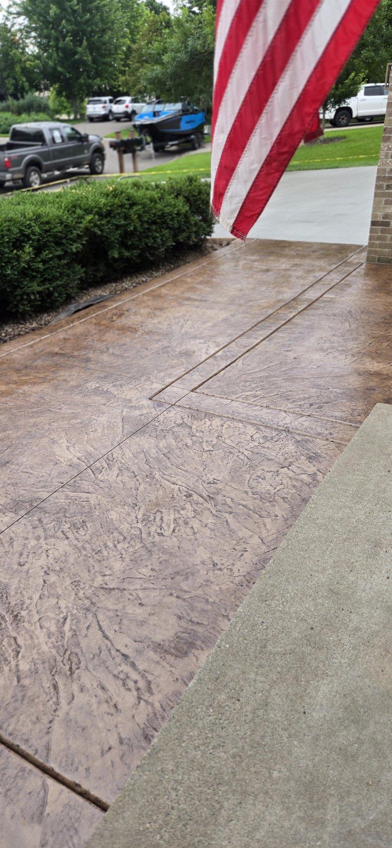 Brown stamped stone-pattern entry walkway with an American flag