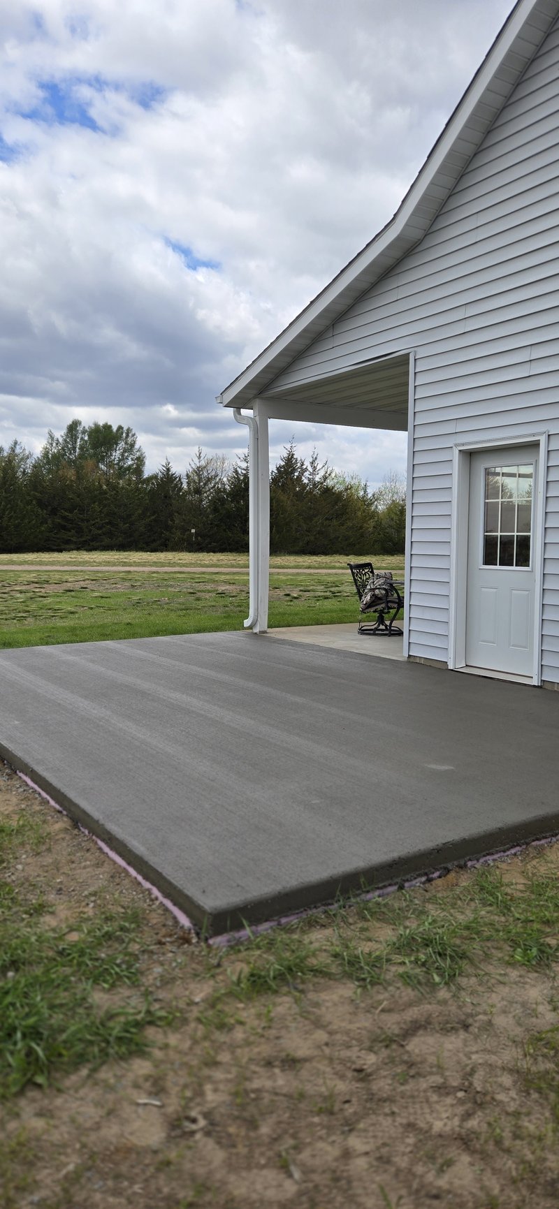 Dark gray broom-finished patio slab under a covered porch overhang