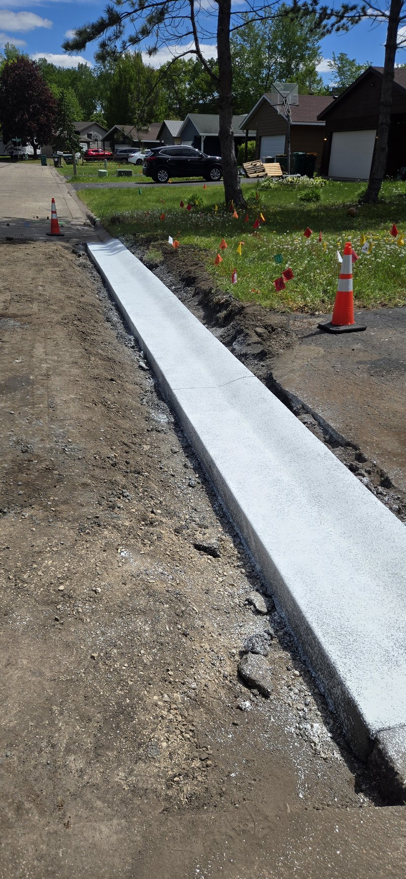 Freshly poured white concrete sidewalk strip along a street curb