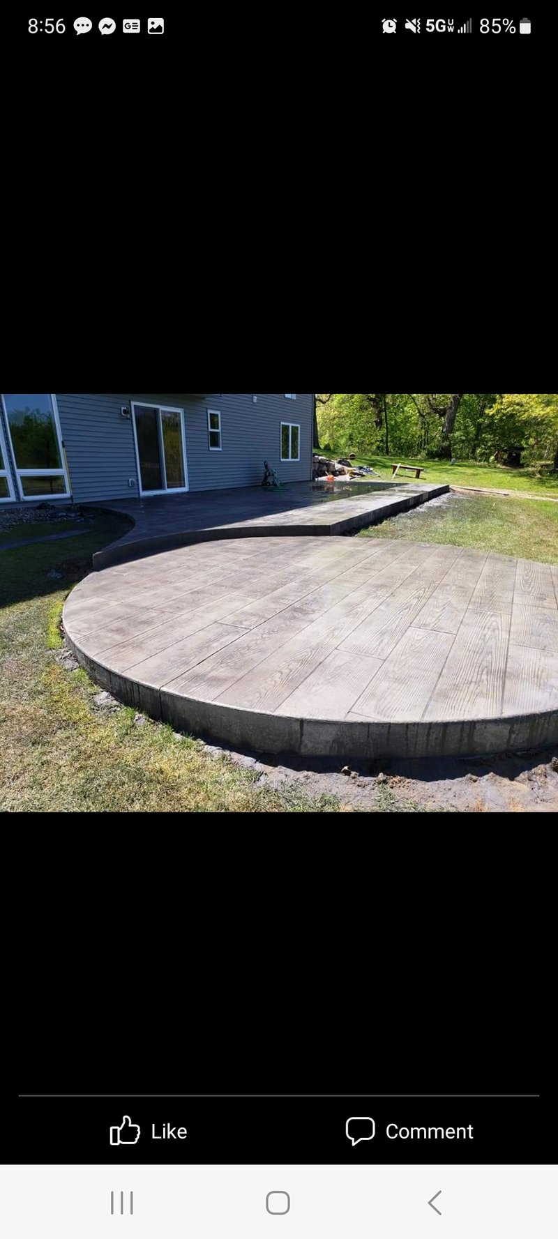 Large round stamped wood-plank patio connecting to a rectangular slab by a walkout
