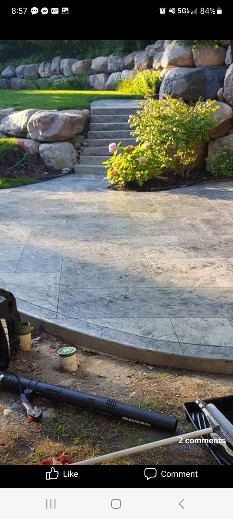 Curved stamped stone patio with matching steps set into a boulder retaining wall garden